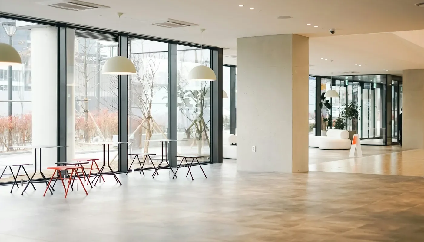 A bright ground floor lobby with full height glazing, pendant lights and pale stone flooring, the kind of shared space a commercial virtual tour starts from