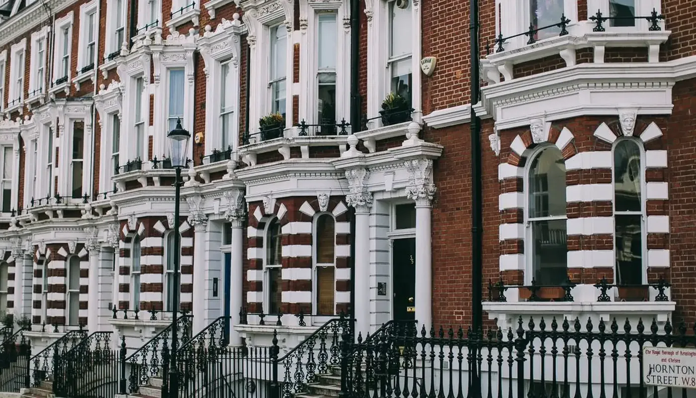 A terrace of red brick and white stucco London houses with black iron railings